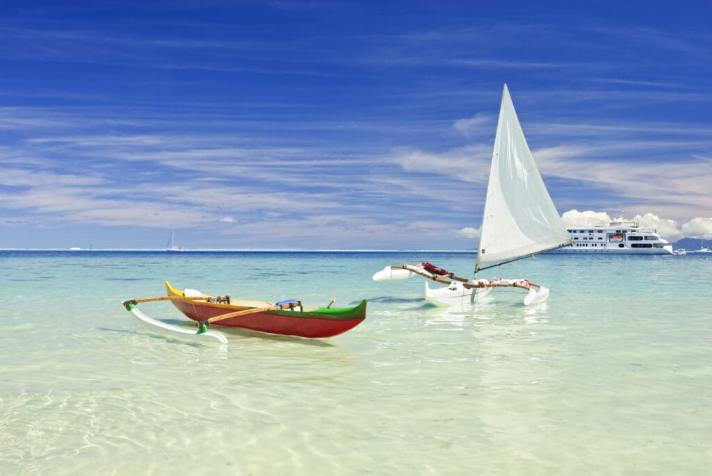 Outrigger canoes on white sand beach in the south pacific. Huahine, French Polynesia